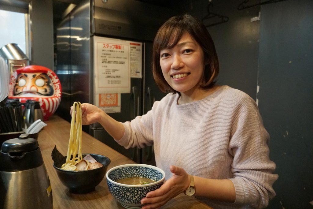大田区のラーメンを食べる女性